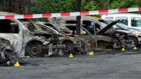 Wracks ausgebrannter Autos stehen auf einem Parkplatz hinter Absperrband. Die Fahrzeuge wurden in der Nacht von unbekannten Tätern angezündet